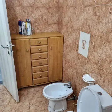 Kupatilo obloženo keramičkim pločicama sa toaletom, bideom i drvenom komodom. - image 7