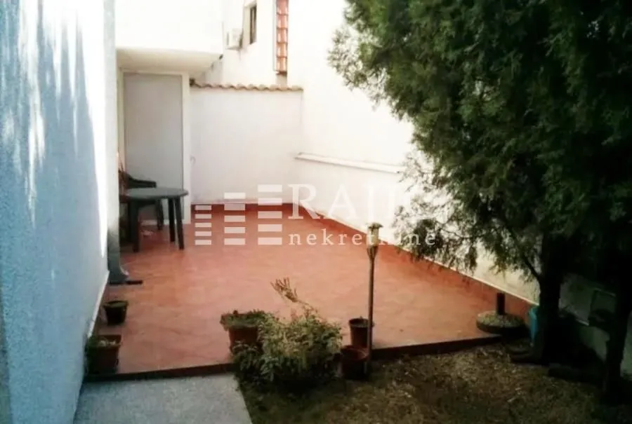 Tiled courtyard with a table and greenery.