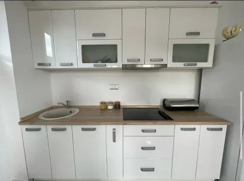 Small white kitchen with a wooden countertop and built-in appliances. - image 8