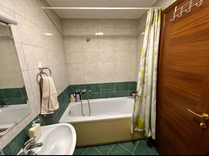 Kupatilo sa kadom, umivaonikom i pločicama u zelenim i bijelim tonovima.