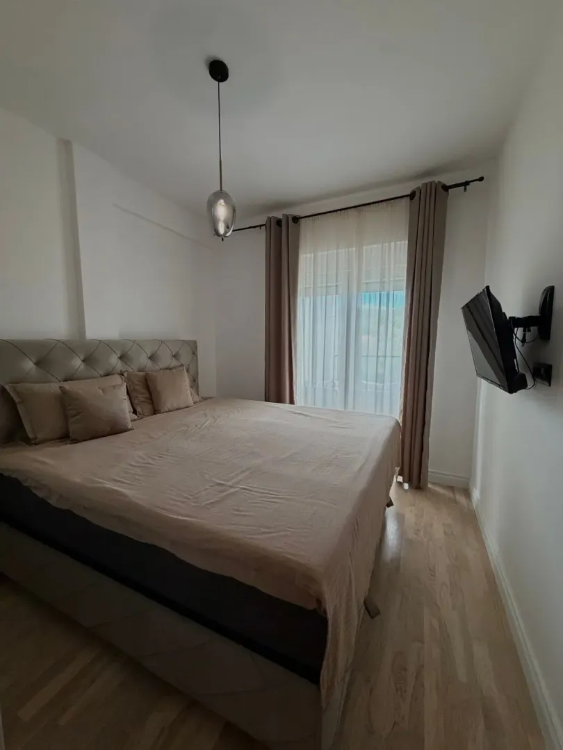 A furnished bedroom with a double bed and a window with curtains.