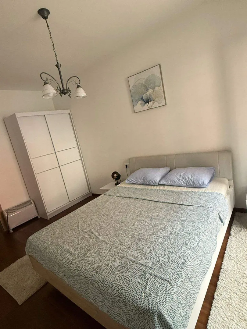 A bright bedroom with a double bed and a white wardrobe.