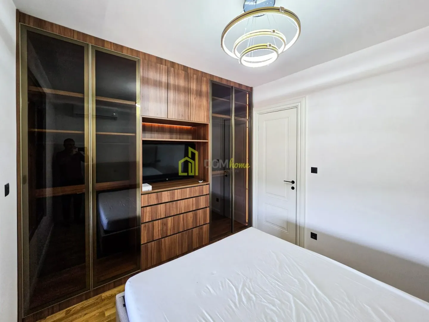 Modern bedroom with built-in wardrobes, a bed, and decorative lighting.