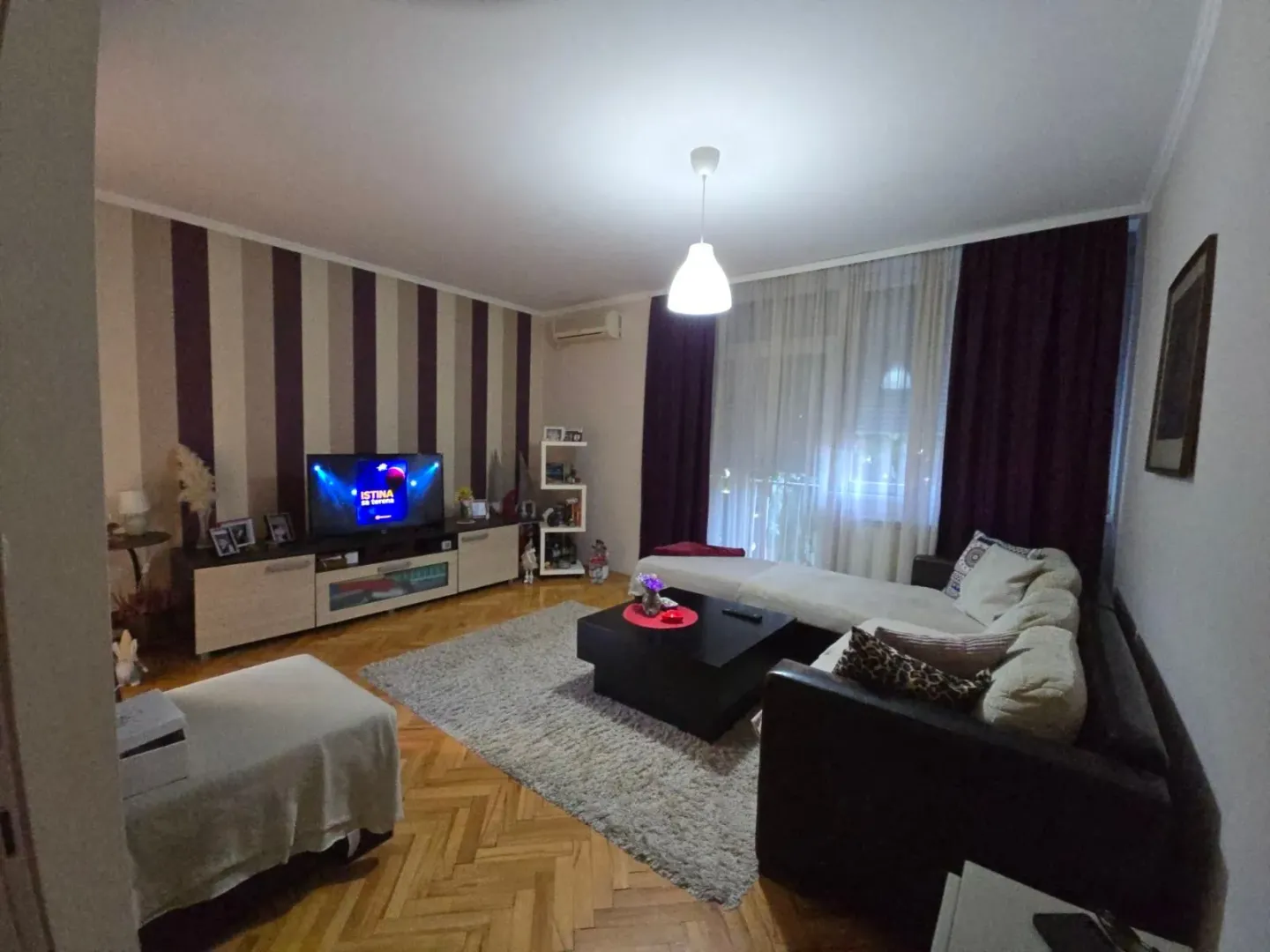 Nameštena dnevna soba sa garniturom i televizorom.