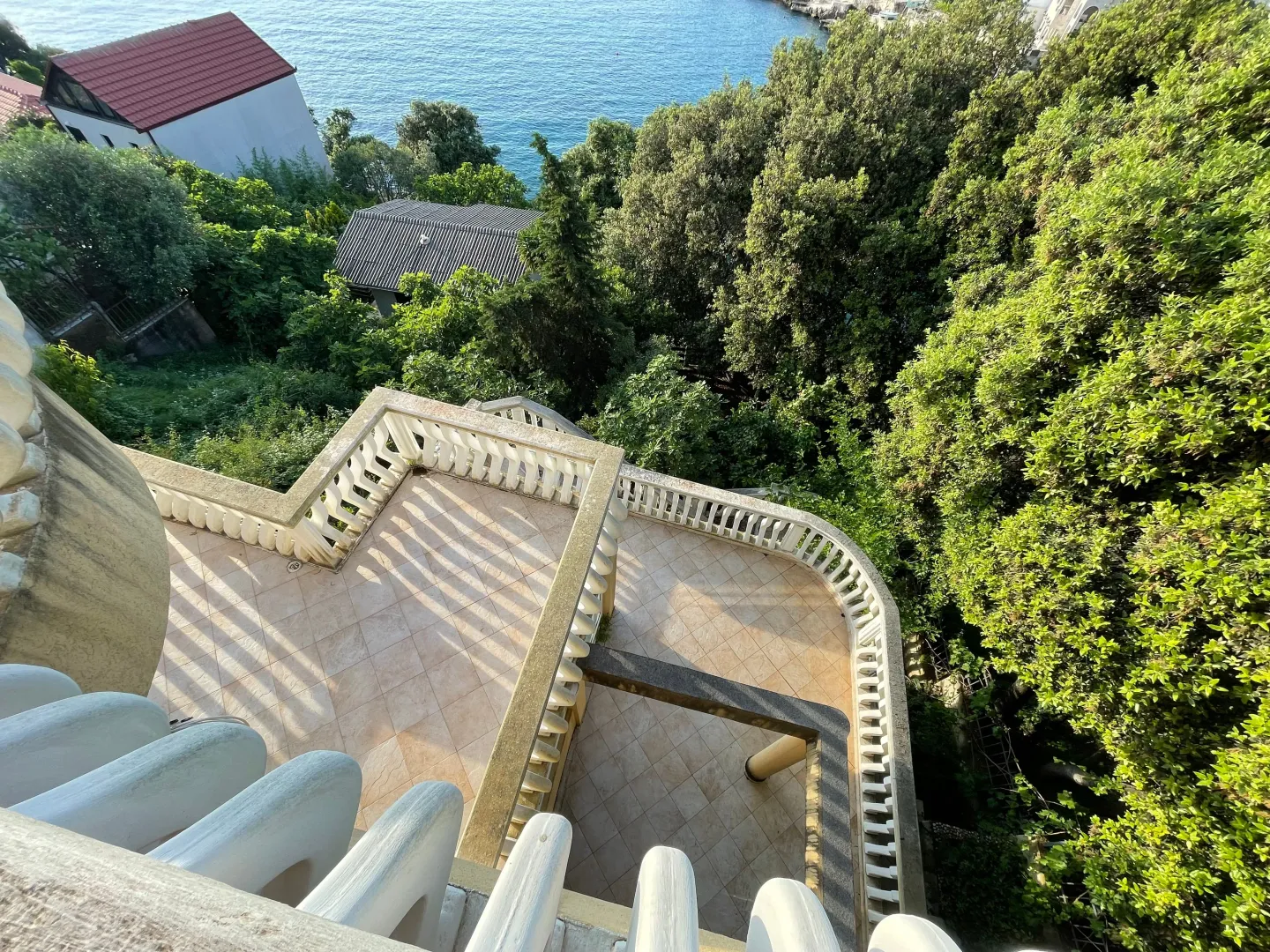 Velika terasa sa balustradama i pogledom na zelenilo i more.