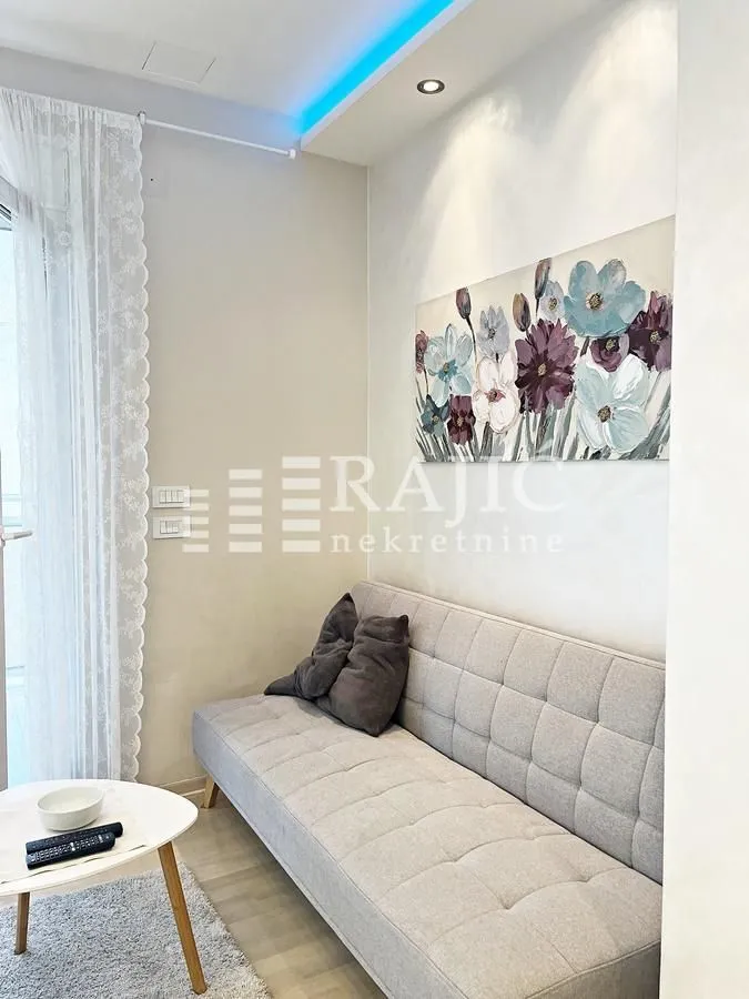 Living room with a grey sofa, coffee table, and a wall painting.