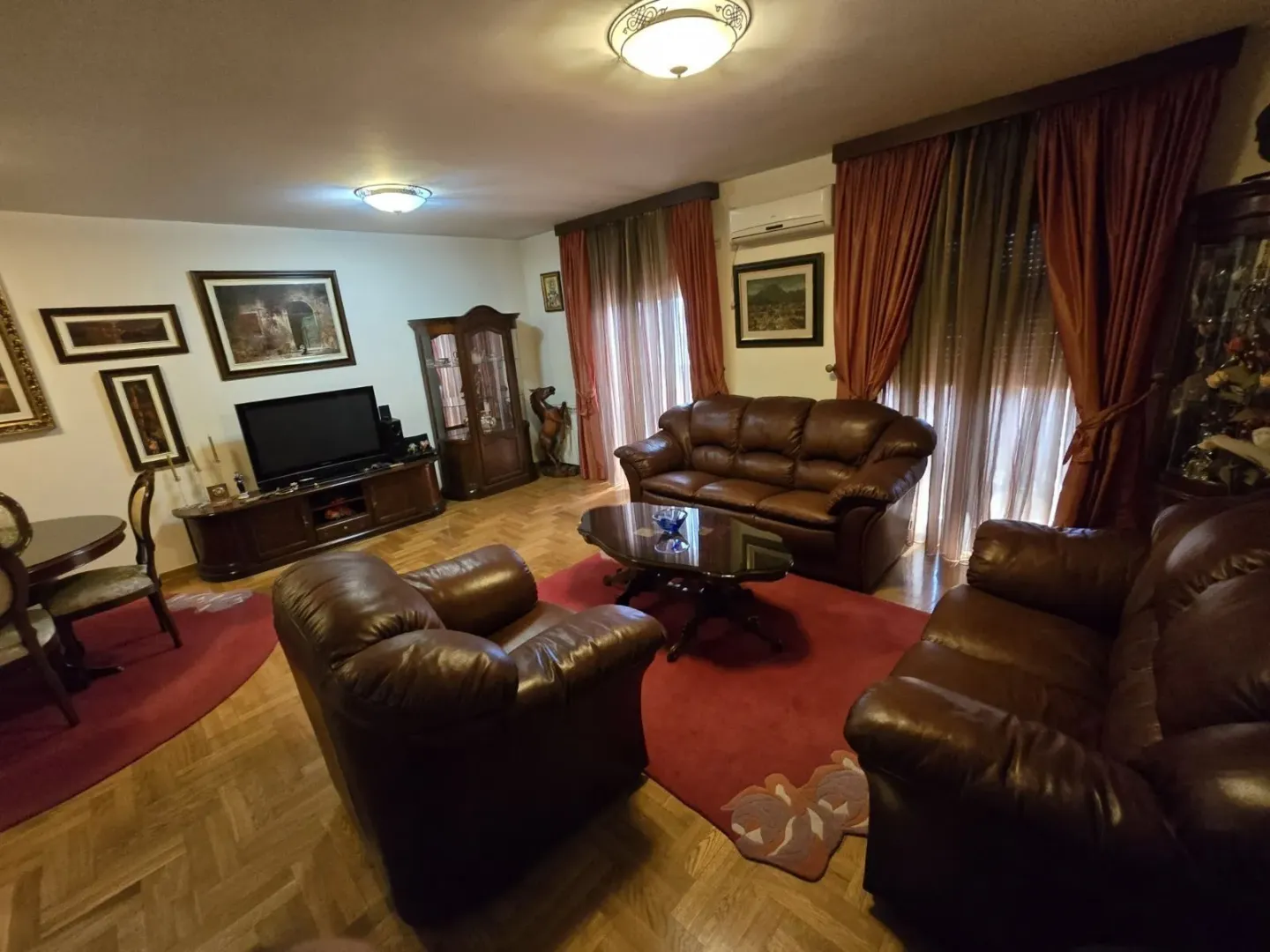 Spacious living room with leather sofas and wooden furniture.