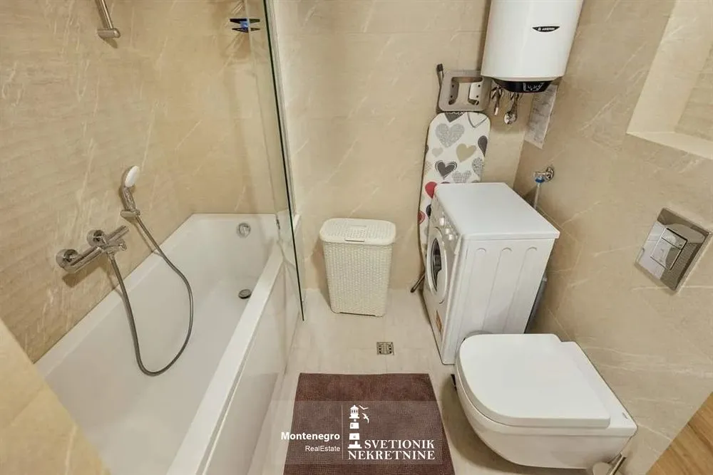 Moderne kupatilo opremljeno kadom, wc šoljom i veš mašinom.