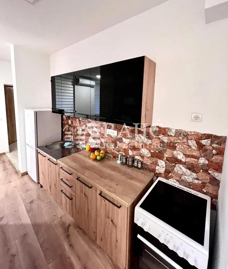 Modern kitchen with wooden lower cabinets and black upper cabinets.