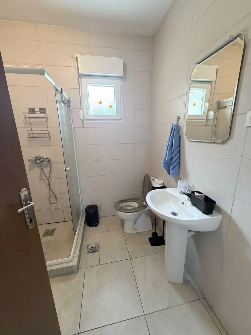Smaller bathroom with a shower cabin, washbasin, and toilet.