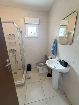 Smaller bathroom with a shower cabin, washbasin, and toilet. - image 8