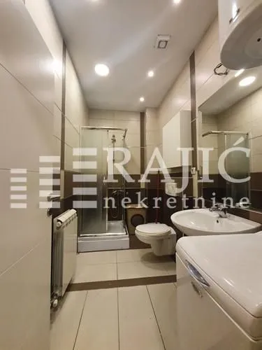 View of a modernly equipped bathroom with a shower cabin and a washing machine.