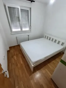 Spavaća soba sa bračnim krevetom, belim zidovima i drvenim podom. - image 8