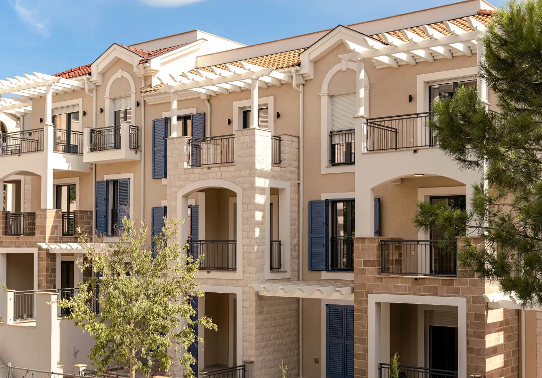 Eksterijer moderne stambene zgrade sa terasam i plavim šalokatima.