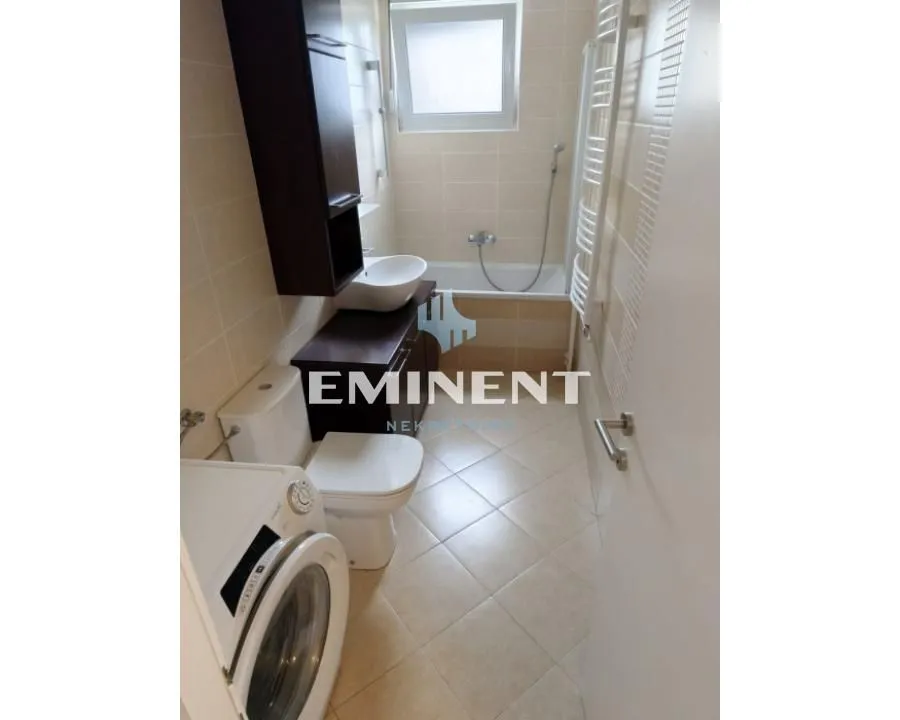 Small bathroom equipped with sanitary facilities, bathtub, and washing machine.