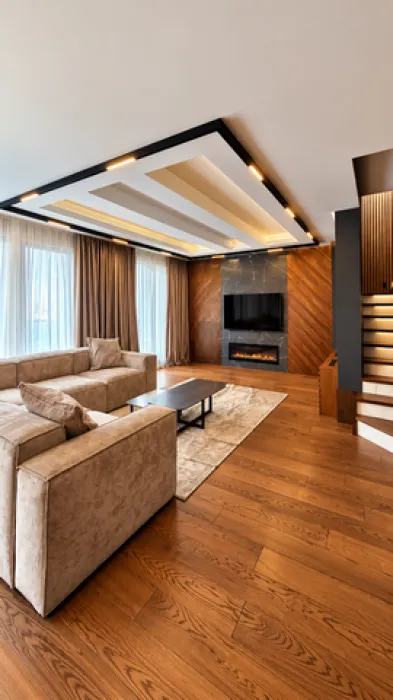 Modern living room with a sofa, TV, and decorative ceiling lighting.