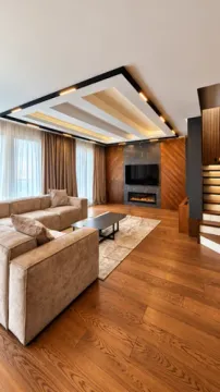 Modern living room with a sofa, TV, and decorative ceiling lighting. - image 13