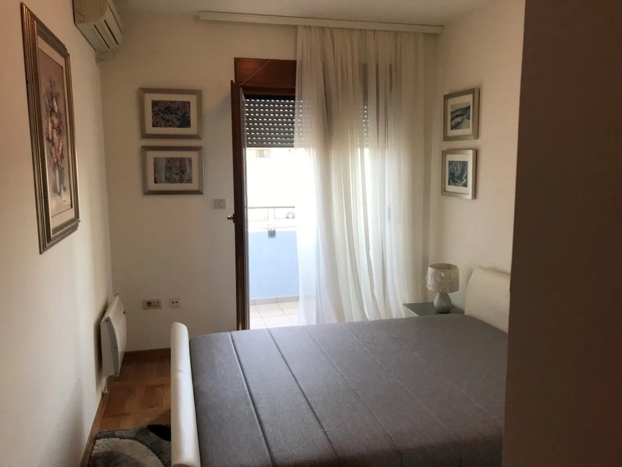 Jednostavno namještena spavaća soba sa bračnim krevetom i izlazom na balkon.