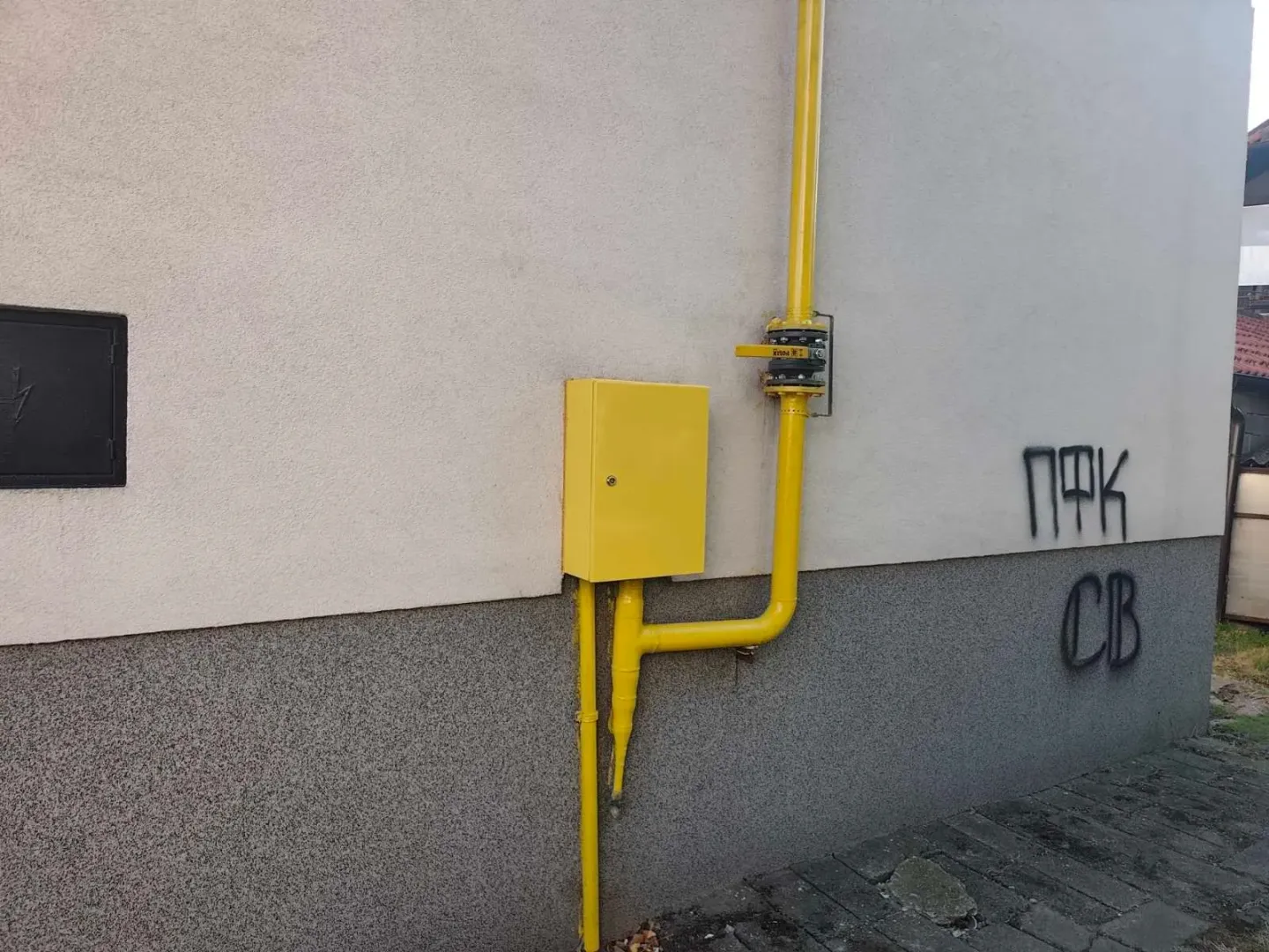 Spoljašnji zid kuće sa instalacijom gasne cevi i ormarićem.