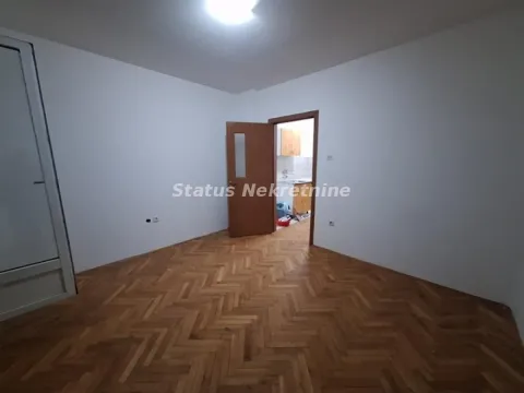 Prazna soba sa parketom i otvorenim vratima koja vode u drugu prostoriju. - image 5