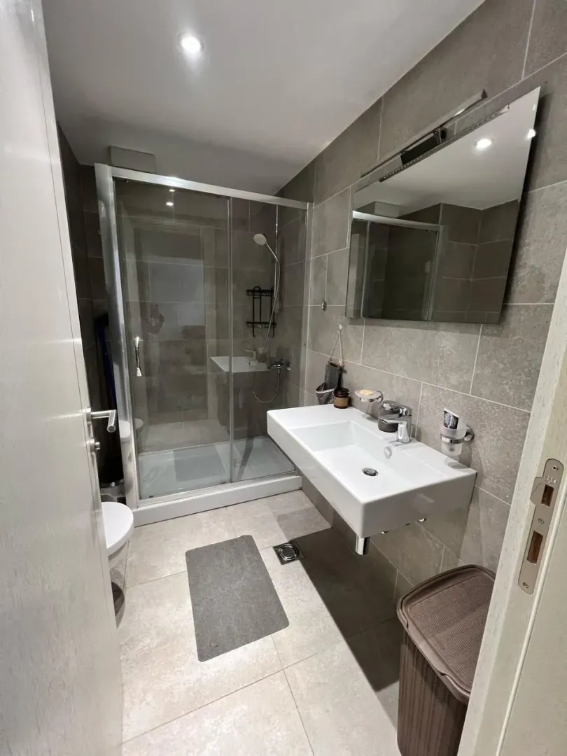 Modern bathroom with a walk-in shower, washbasin, and mirror.