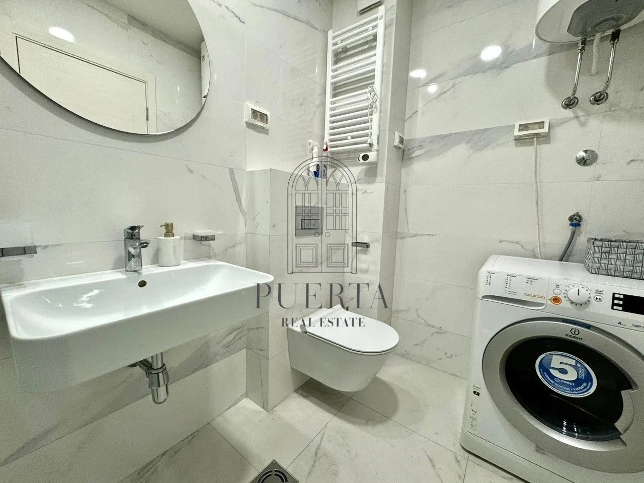 Modern bathroom with a sink, toilet, and washing machine.