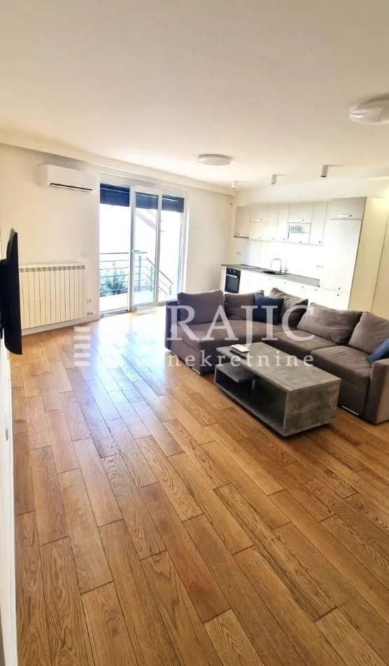 Spacious living room connected to the kitchen, featuring hardwood flooring and access to the terrace.
