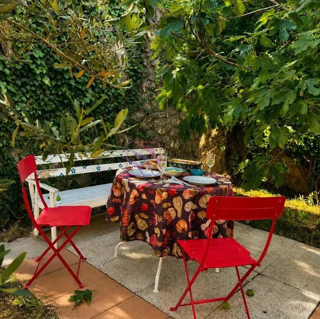 Garden with a dining table and chairs in the shade of trees.
