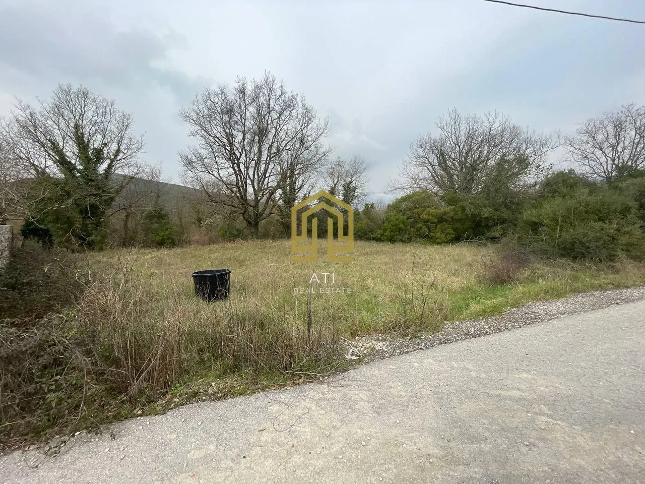 Pogled na plac sa putem u prednjem dijelu i rastinjem.