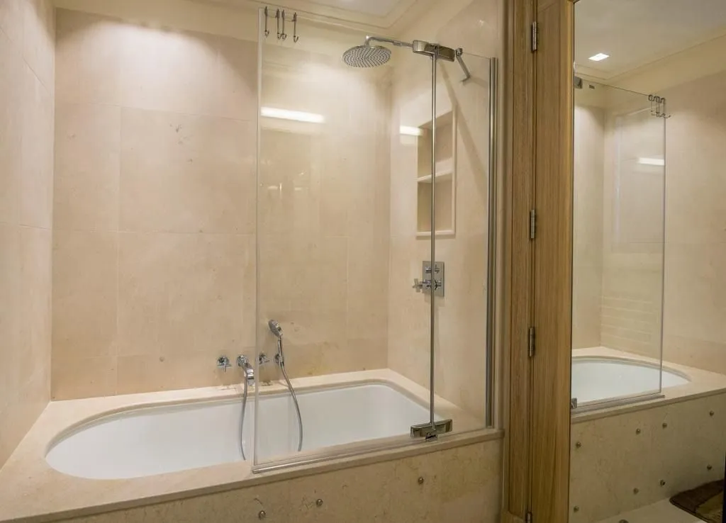Bathroom with a bathtub and a glass shower partition.