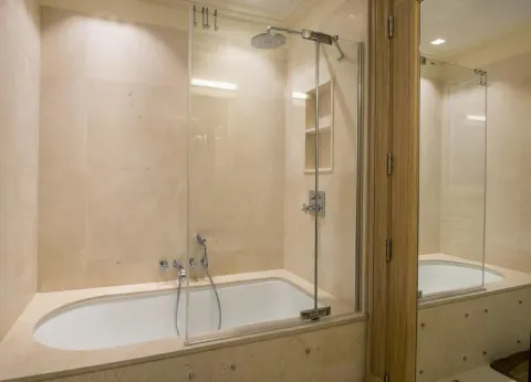 Bathroom with a bathtub and a glass shower partition. - image 11