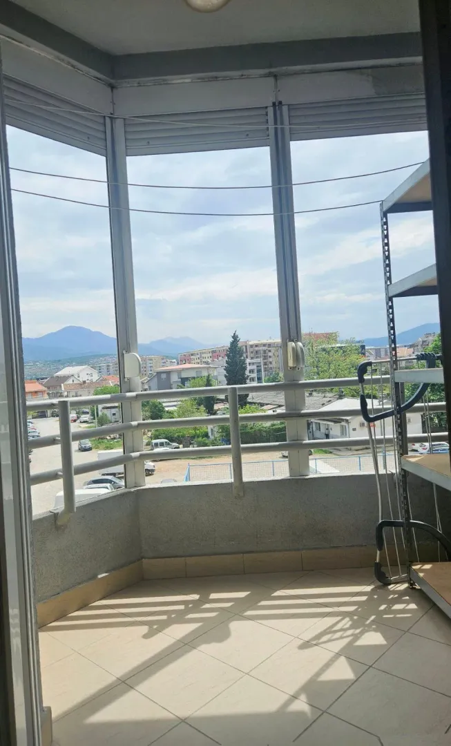 Zastakljena terasa sa pogledom na grad i okolne planine.