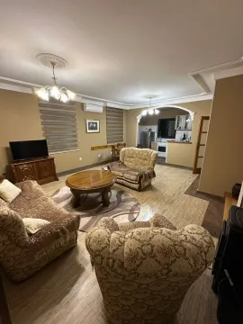 Living room with furniture and a kitchen in the background. - image 4