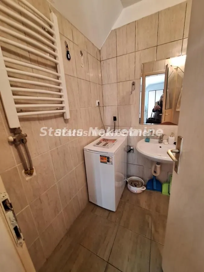 Smaller tiled bathroom equipped with a washbasin and a washing machine.