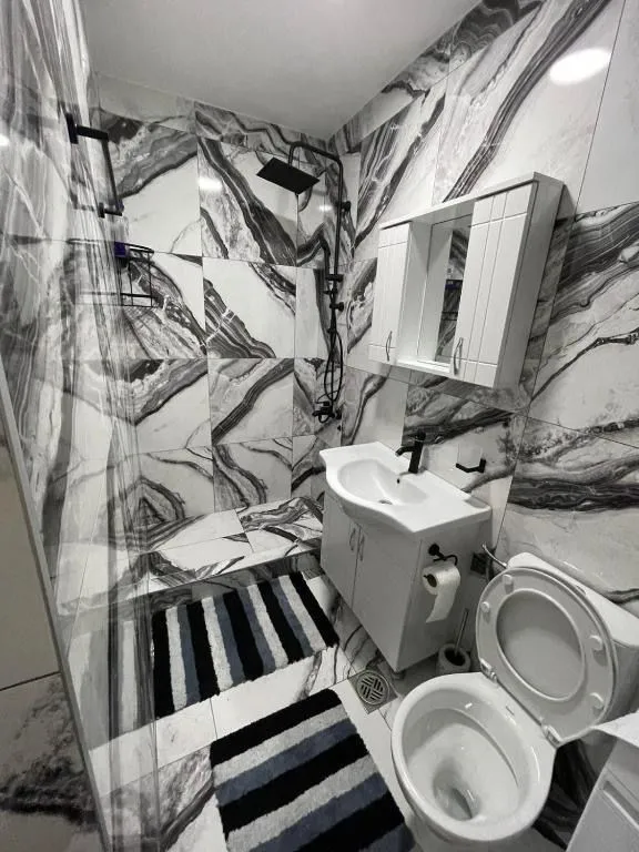 Modern bathroom equipped with a walk-in shower and marble tiles.