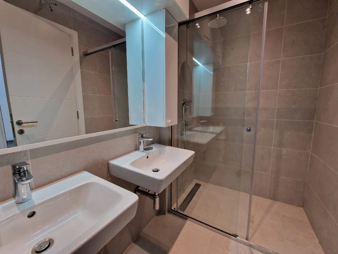 Modern bathroom equipped with a shower cabin and two washbasins.
