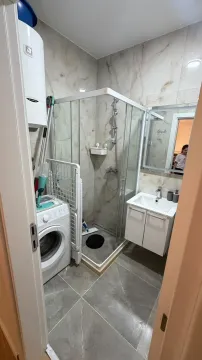 Manje uredno kupatilo sa tuš kabinom, umivaonikom i mašinom za veš. - image 5