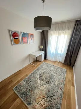 Small bedroom with a desk and a rug on the floor. - image 7
