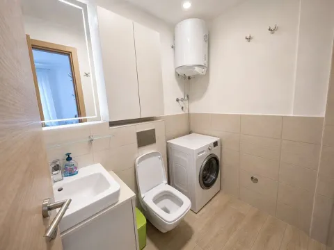 Bathroom with a sink, toilet, washing machine, and water heater. - image 4