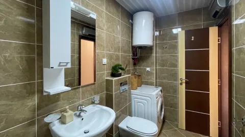 Kupatilo opremljeno sanitarijama, umivaonikom, ogledalom i mašinom za veš. - image 11
