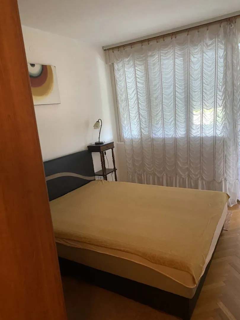 Jednostavno namještena spavaća soba sa bračnim krevetom i noćnim ormarićem.