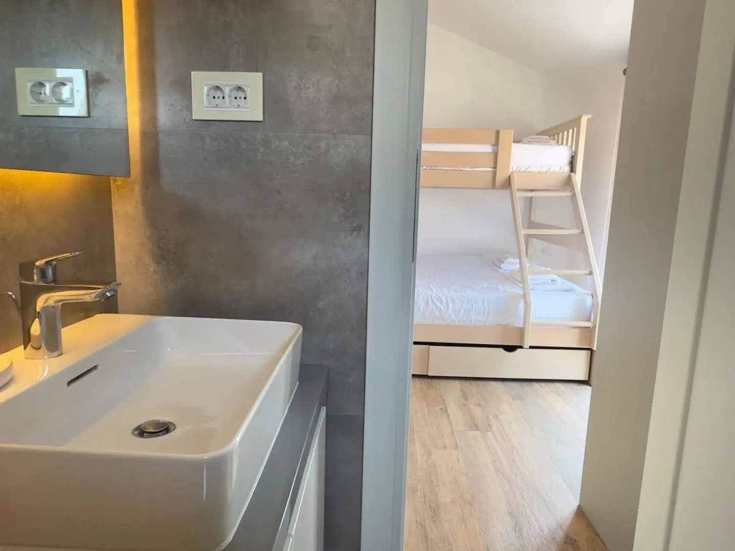 View from the bathroom into a bedroom with a bunk bed.