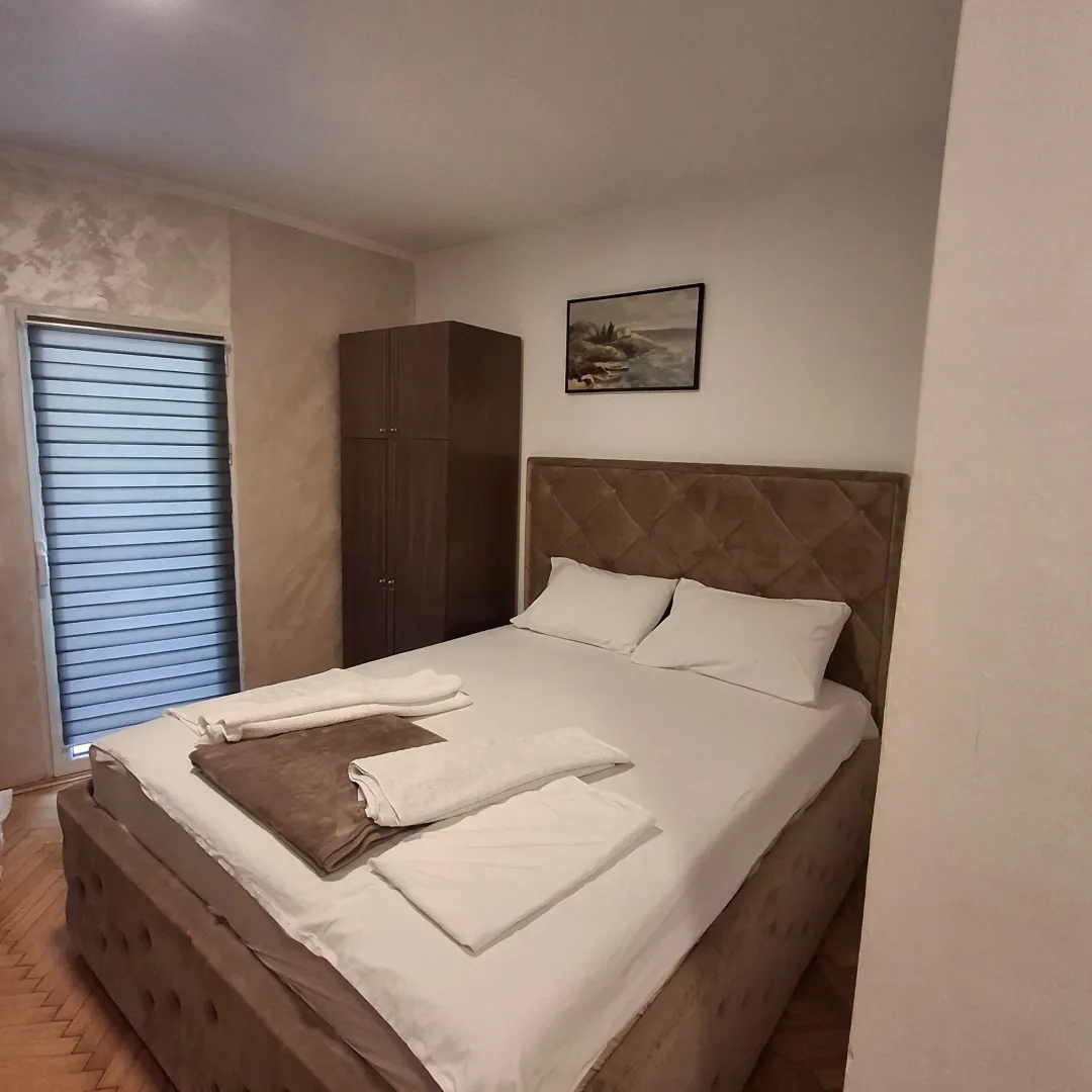 Spavaća soba sa bračnim krevetom, ormarom i prozorom.