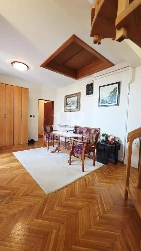 Dnevni boravak sa trpezarijskim stolom, drvenim nameštajem i parketom na podu.