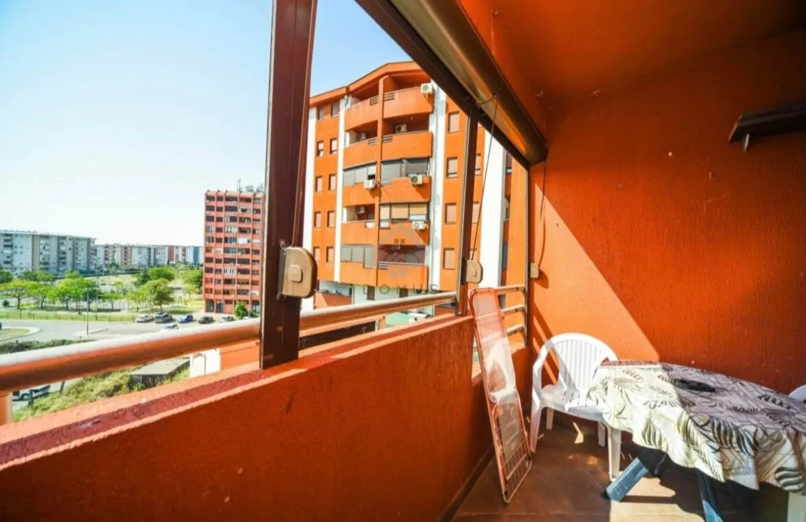 Covered balcony space with a table, chairs, and a view of buildings.