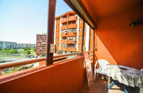 Covered balcony space with a table, chairs, and a view of buildings. - image 9