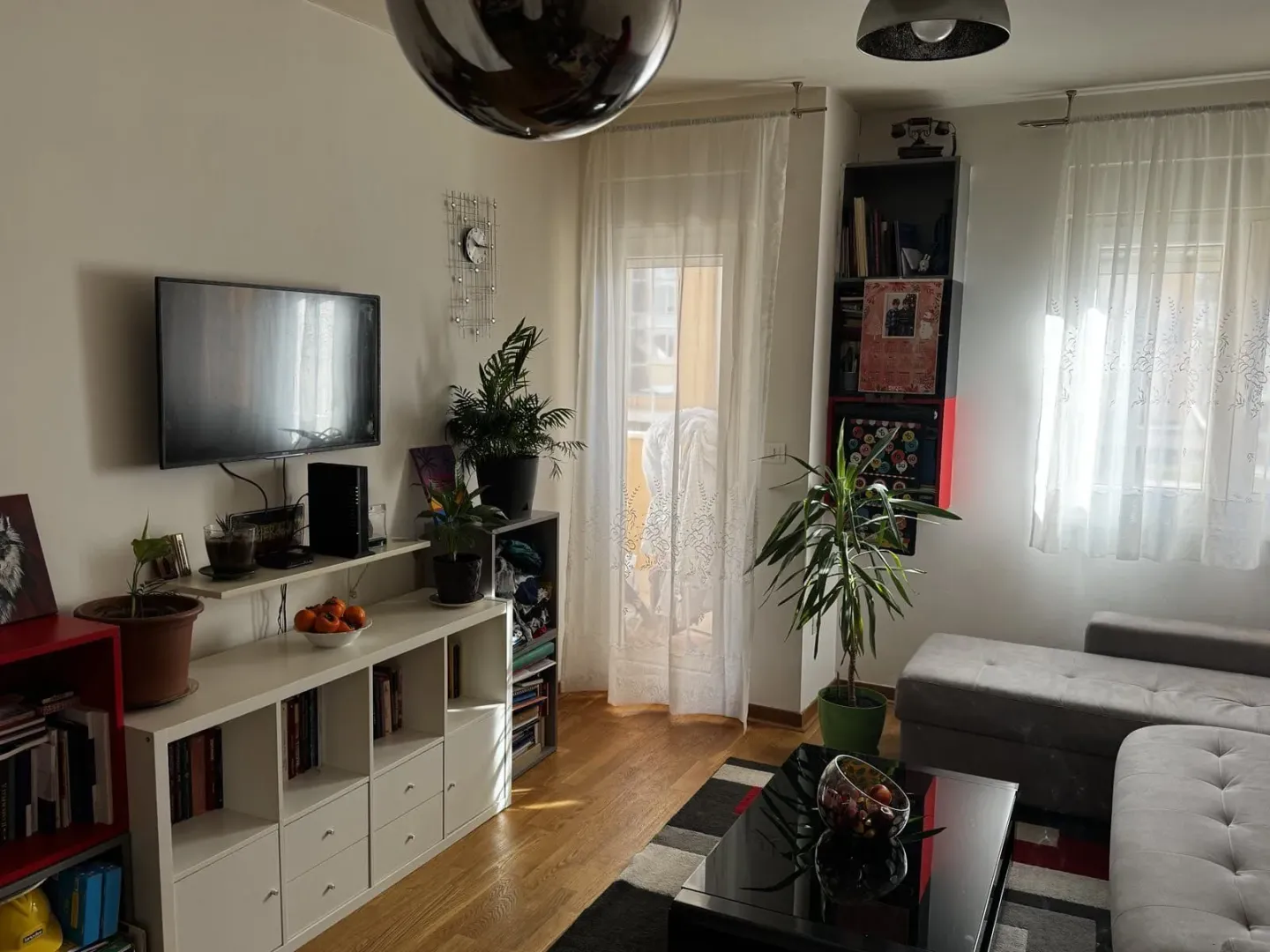 Dnevna soba sa garniturom, TV-om i policama za knjige.
