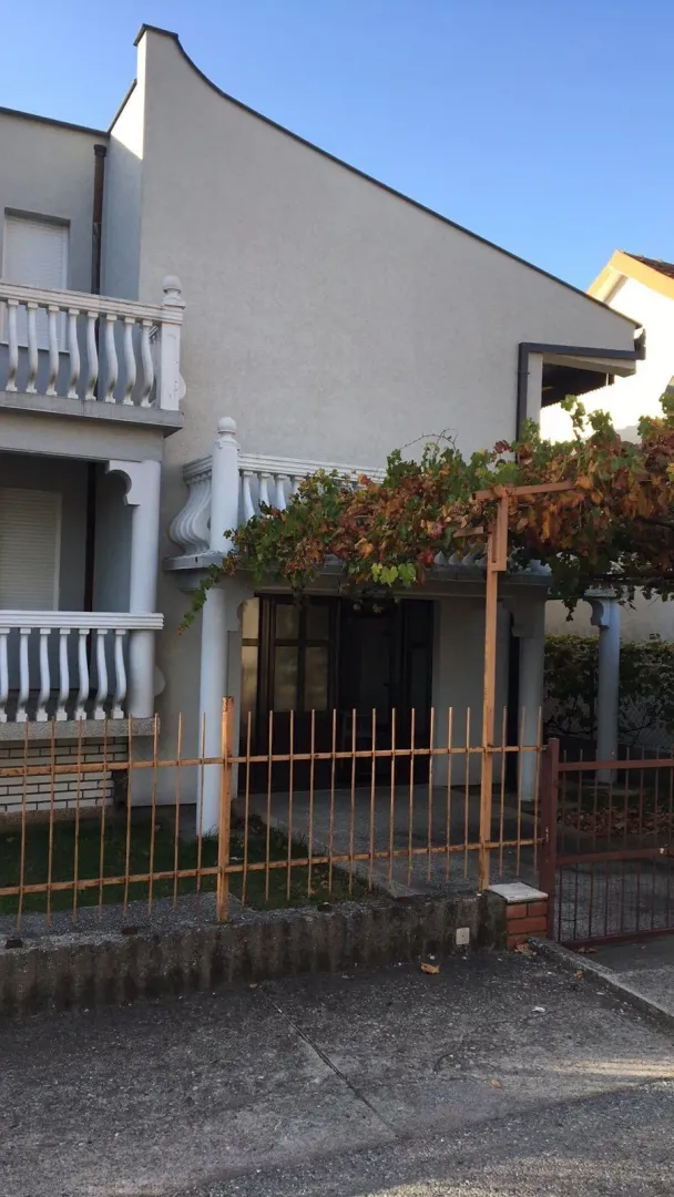 Exterior of a house with a fence and a vine over the entrance.