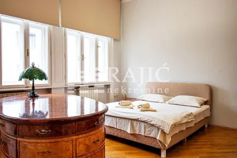 Bedroom with a double bed, large windows, and a wooden desk. - image 15