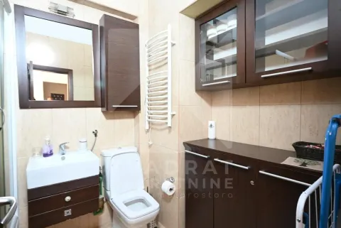 Bathroom with a sink, toilet, towel radiator, and dark wooden cabinets. - image 13